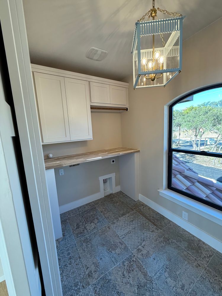 Small home office nook with built-in cabinets, desk, gray carpet, and a large arched window.