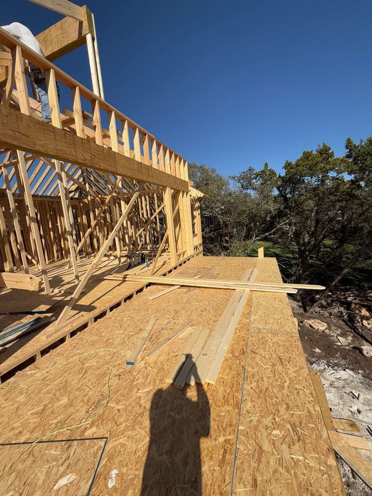 Wood-framed house under construction with plywood flooring and blue sky visible.