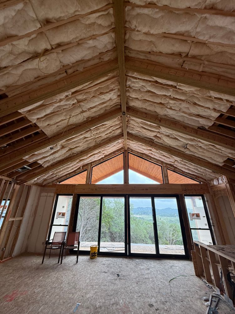 Unfinished attic room with exposed insulation, large windows, and mountain views.