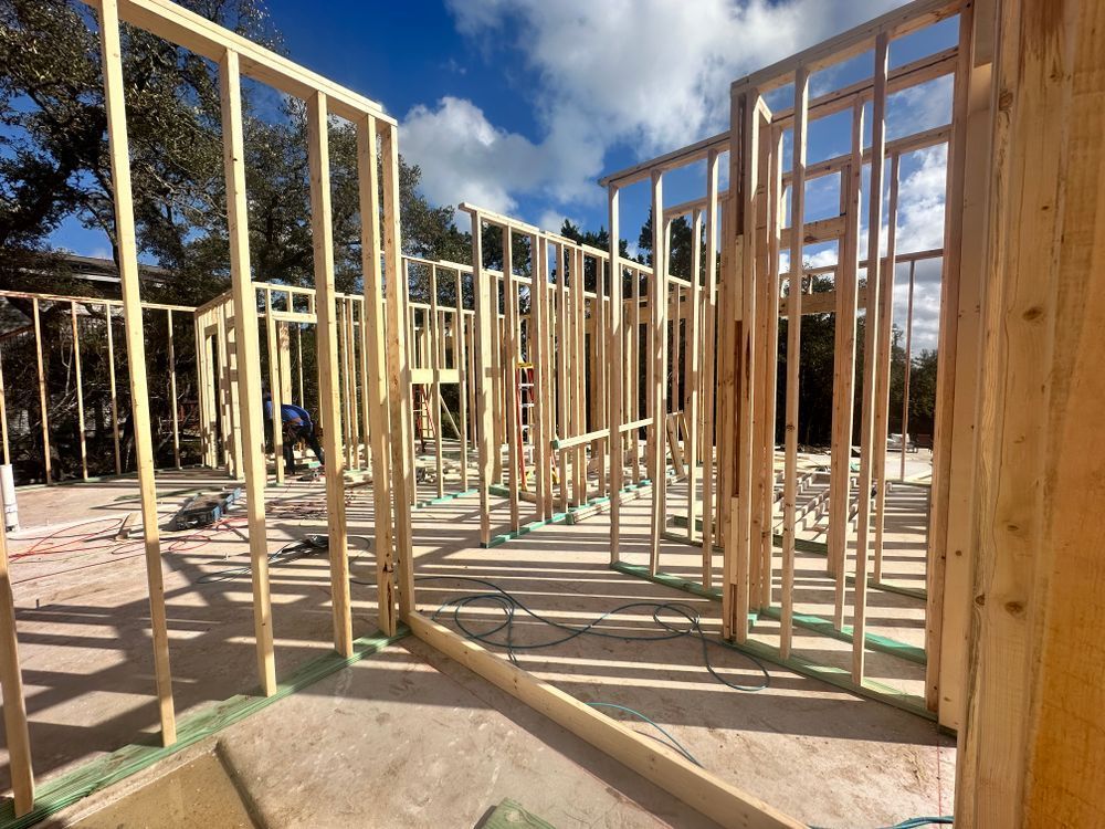 Wood-framed house under construction on a sunny site with blue sky and scattered lumber