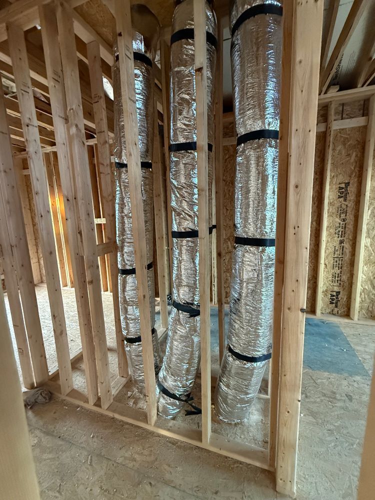 Framed interior wall with insulated HVAC ducts in a construction site