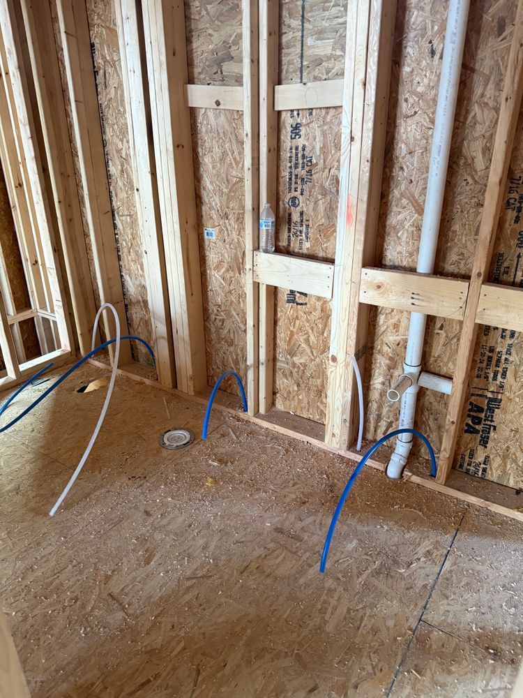 Unfinished room with exposed wooden studs, wiring, and blue electrical cables on the floor.