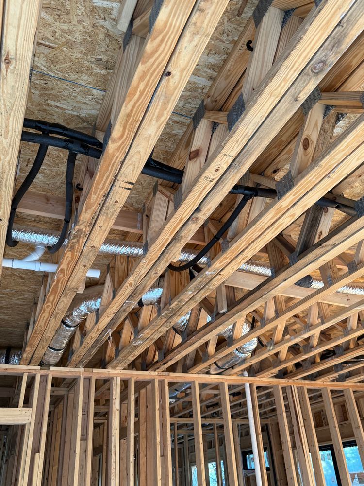 Exposed wooden roof joists and ceiling insulation above unfinished interior wall framing.