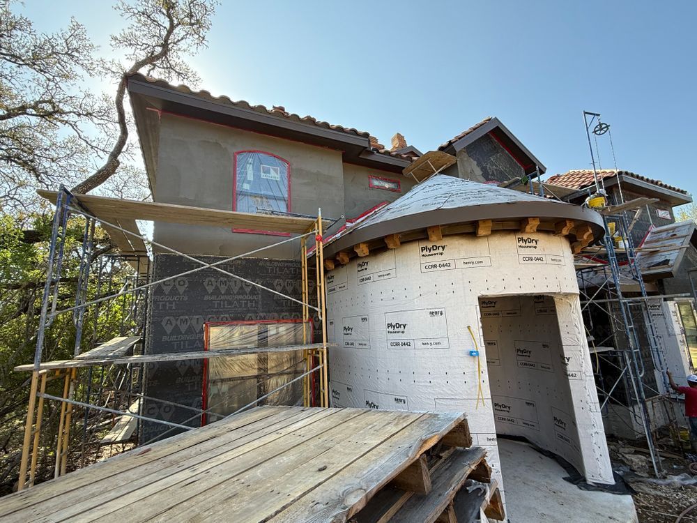House under construction with scaffolding, white wrap, and a wooden ramp in front