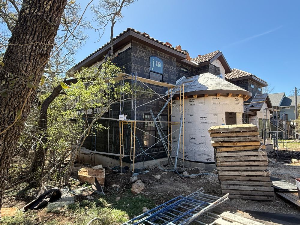 Stone house under renovation with scaffolding and stacked construction materials outdoors