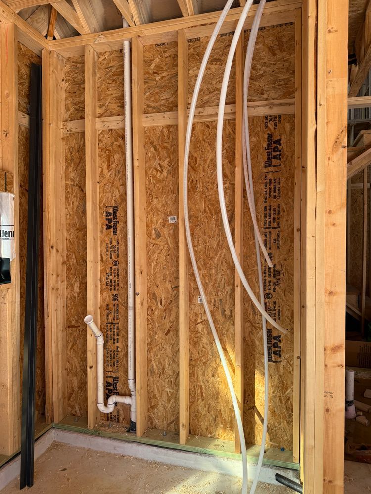 Framed wall under construction with exposed wiring and plumbing in a wooden house interior