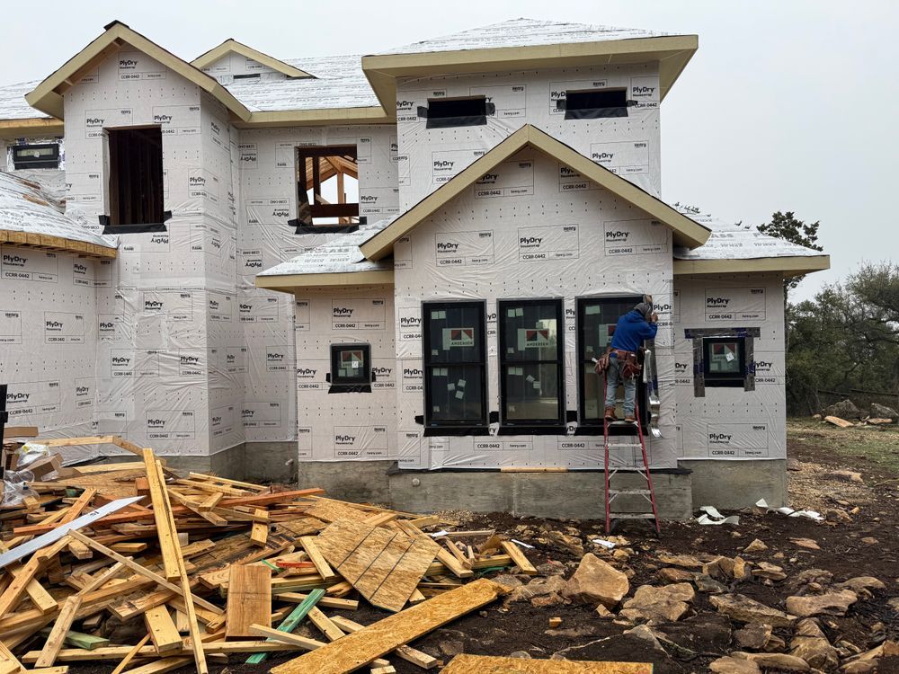 Partially built two-story house under construction with debris and a ladder in the front yard