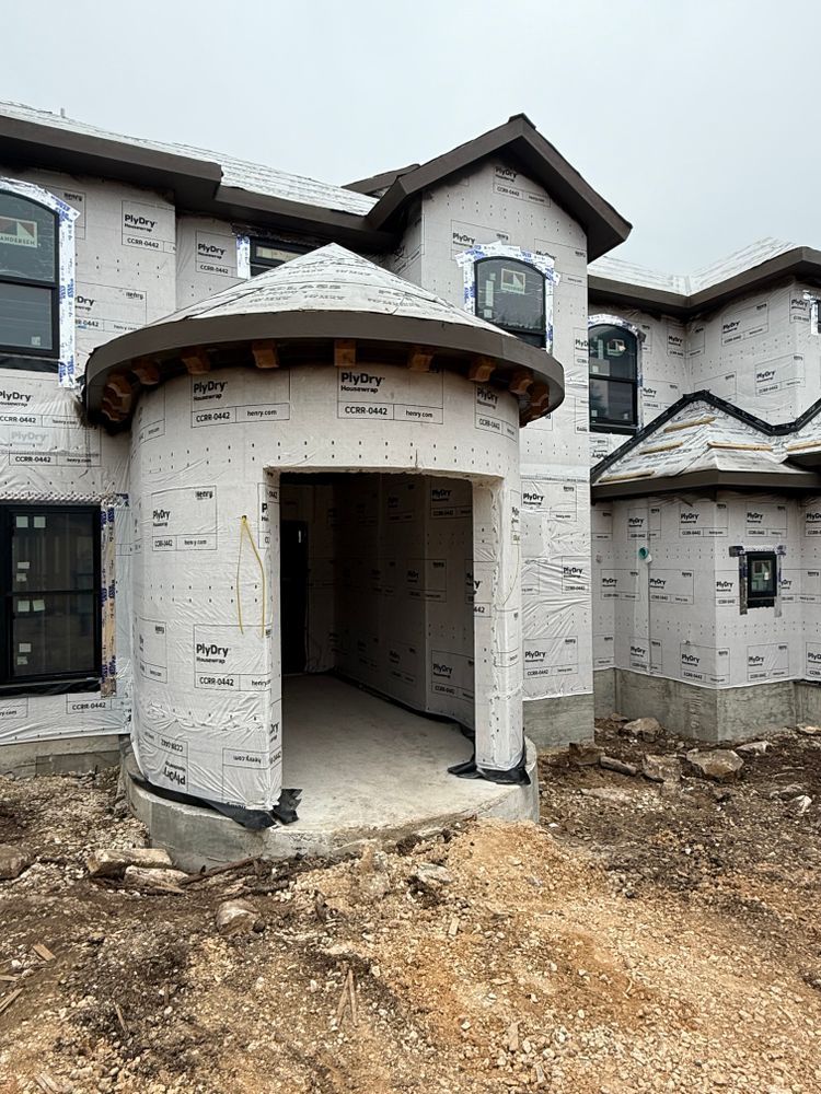 New home under construction with white stucco exterior and a covered front entry.