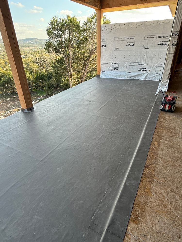Covered porch with a long gray floor covering, wooden posts, and outdoor hillside views.