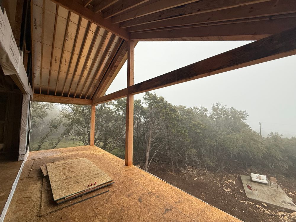 Wooden balcony with a bench overlooking a misty, wooded hillside