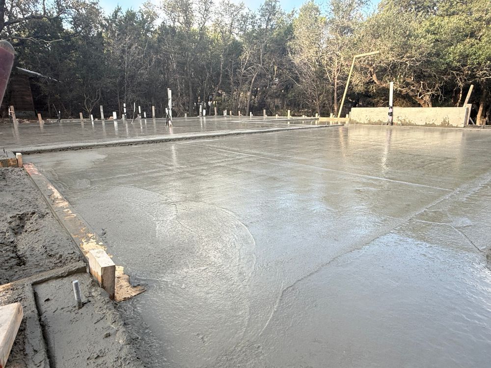 Fresh concrete slab foundation at a construction site with trees in the background