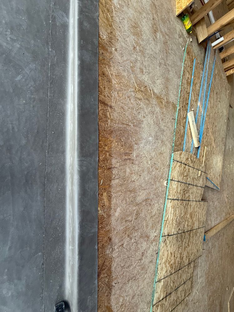 Top-down view of a concrete curb beside a rough dirt construction area with wooden forms and blue stakes.