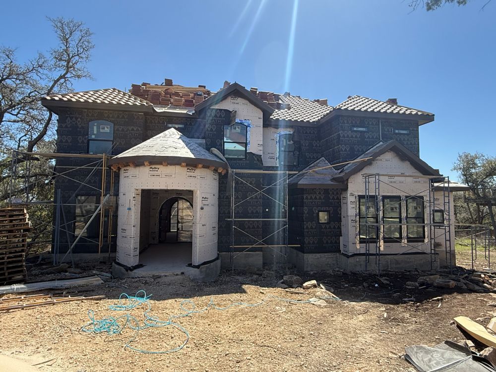 Abandoned, partially demolished house with exposed framing and debris under bright blue sky