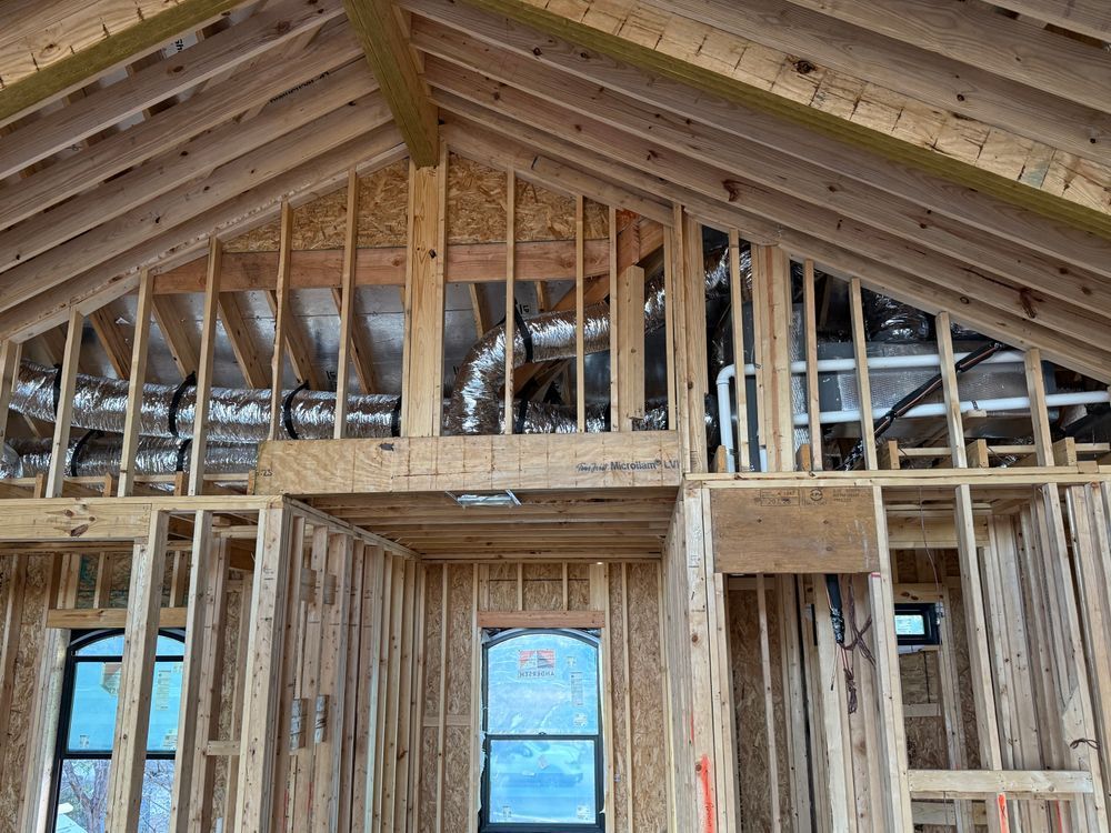 Wood-framed house interior under construction with exposed rafters and unfinished walls