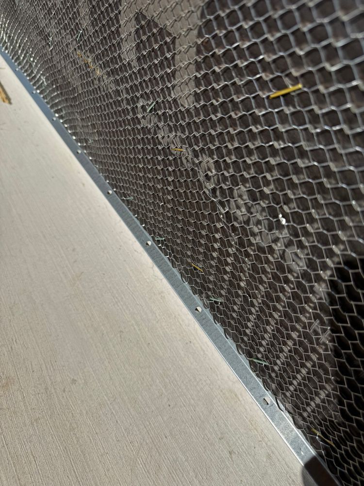 Close-up of a black hexagonal mesh panel beside a light gray wall edge.
