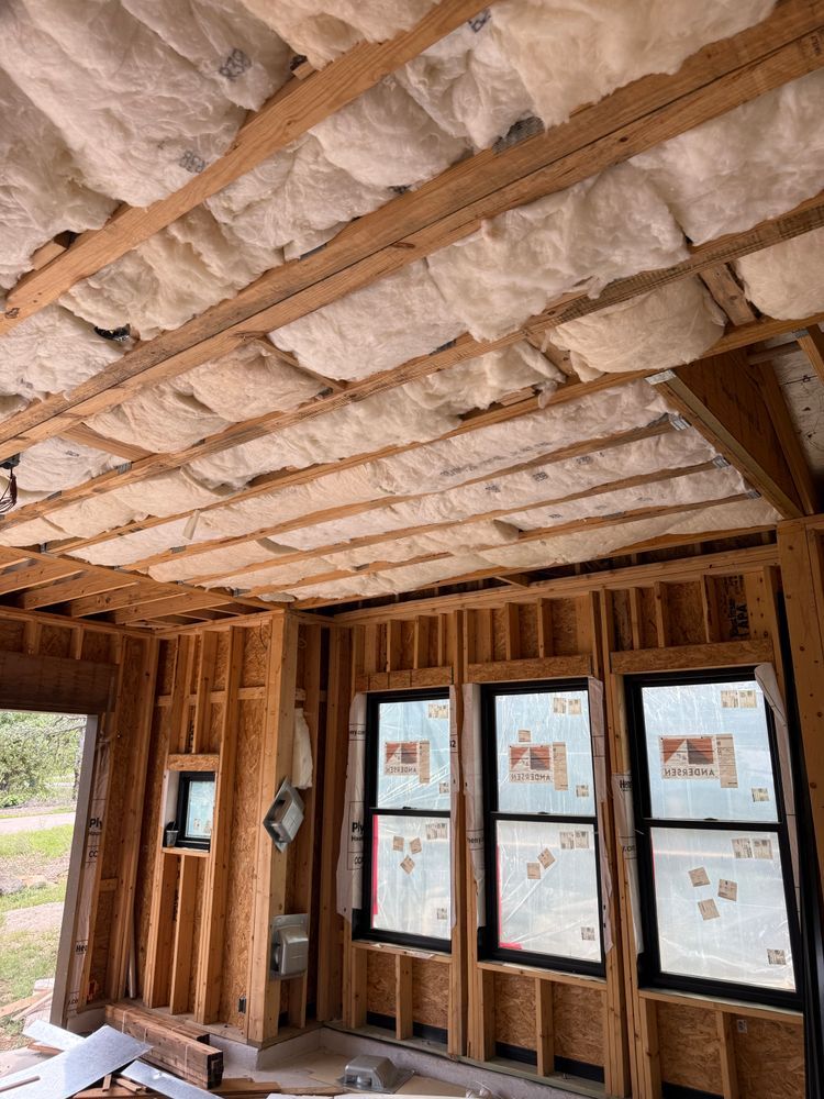 Exposed wood framing and insulation in an unfinished room with multiple windows and daylight outside