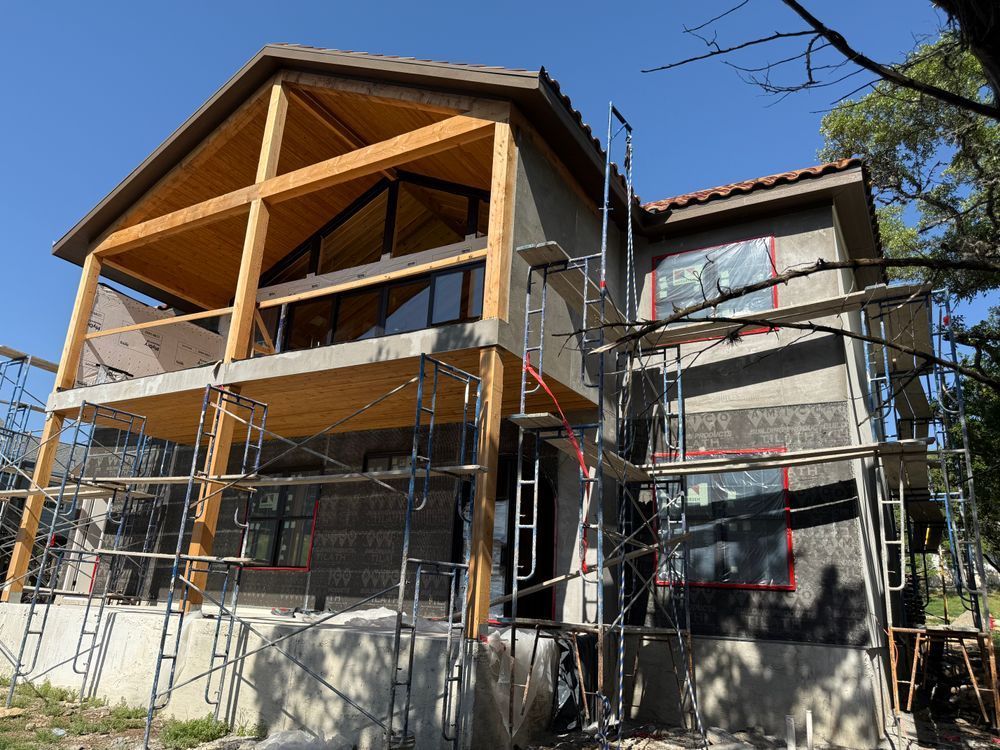 House under construction with scaffolding and exposed wooden framing on the front porch