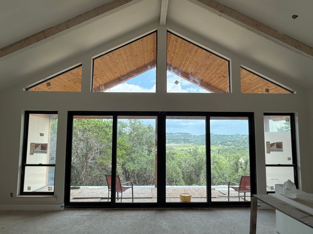 Modern living room with vaulted ceiling and large glass doors opening to a green patio view