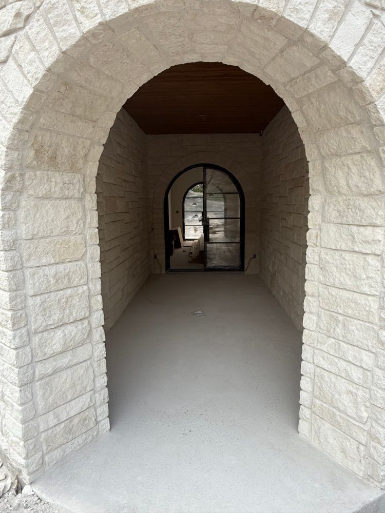 Stone archway hallway leading to a small arched doorway with glass doors beyond.