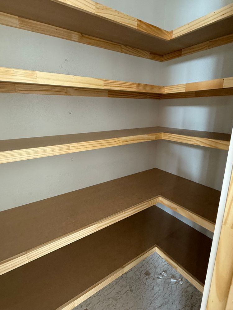 Built-in corner pantry shelves with wood trim and brown shelving, showing an empty storage space.