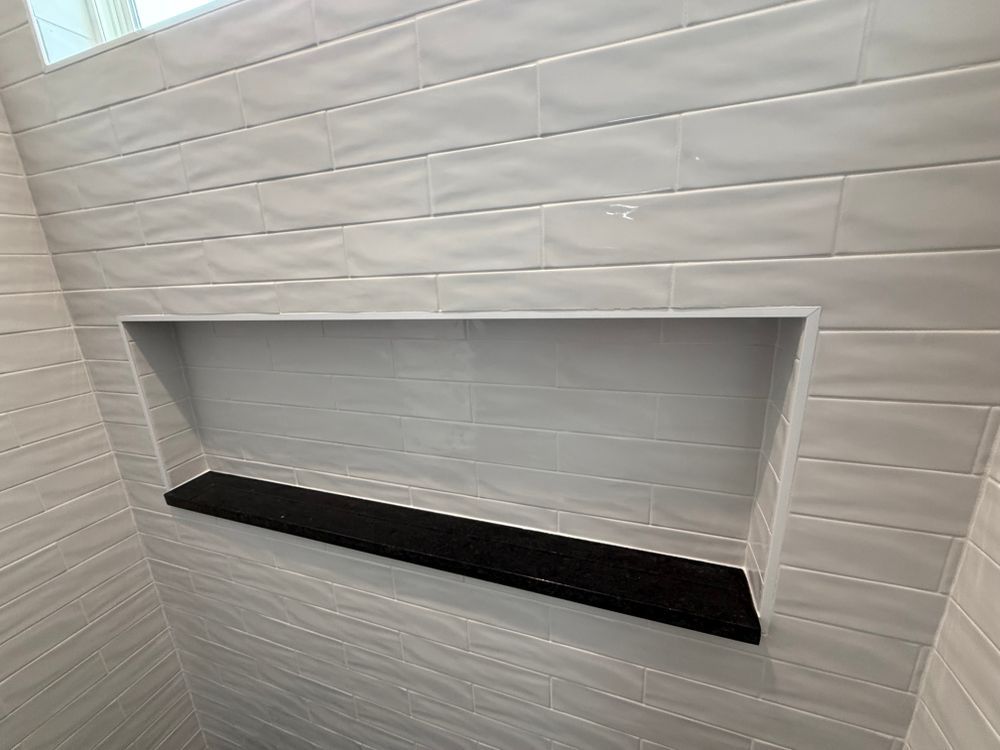 Small rectangular wall niche with a black ledge in a white tiled wall