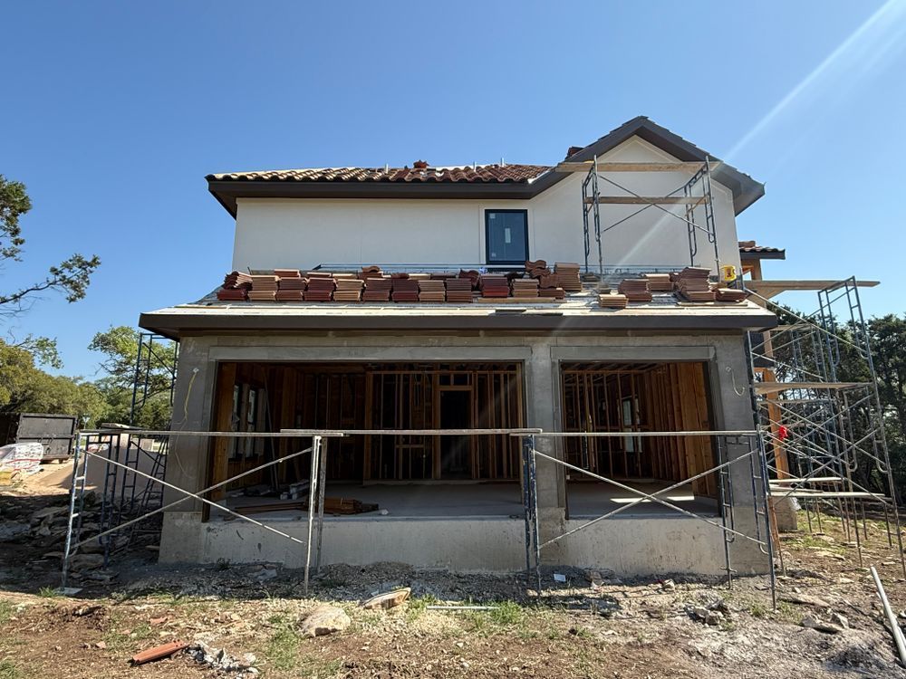 Partially finished two-story house with scaffolding and open front under a clear blue sky