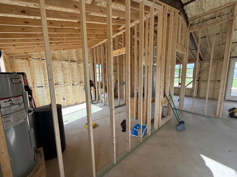 Framed interior of a house under construction with exposed wood studs and concrete floor