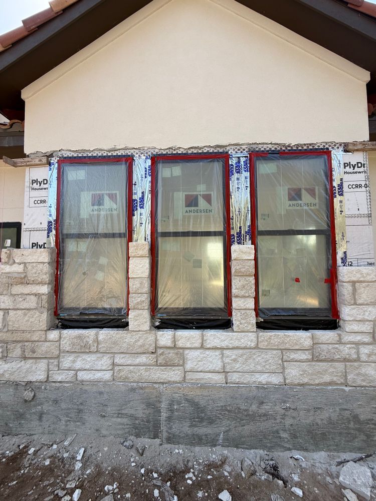 Front view of a house with three tall windows and a stone base under construction