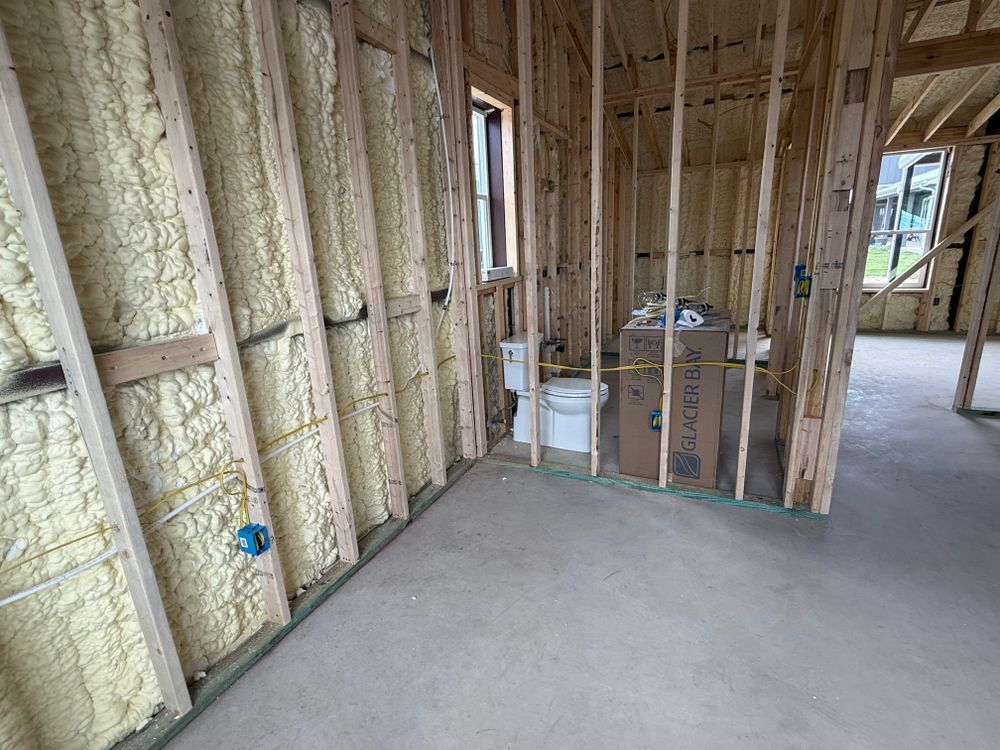 Unfinished room with exposed insulation, studs, concrete floor, and a window in the distance