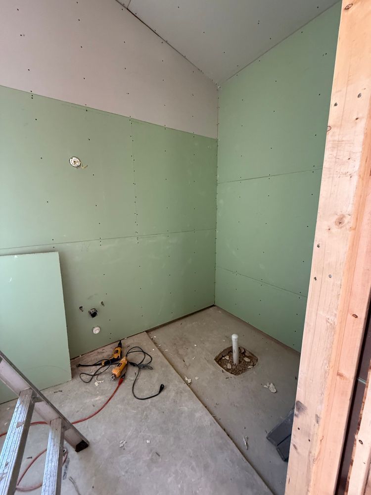 Unfinished bathroom or utility room with green drywall, exposed plumbing, and construction tools on the floor