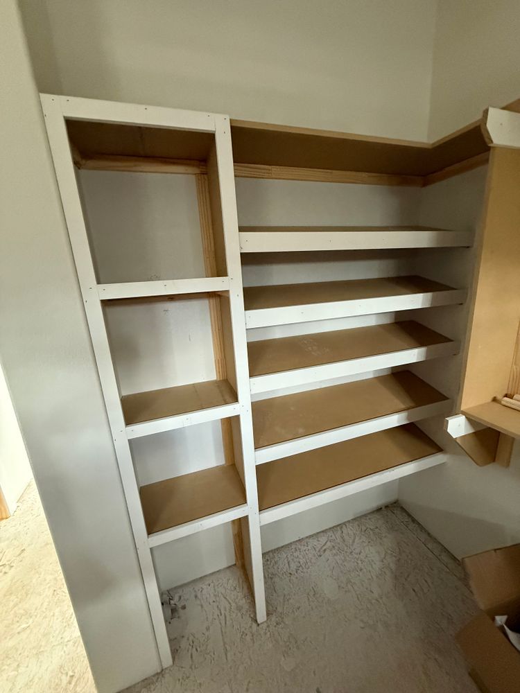 Empty beige closet with built-in shelves and hanging space, viewed from the doorway.