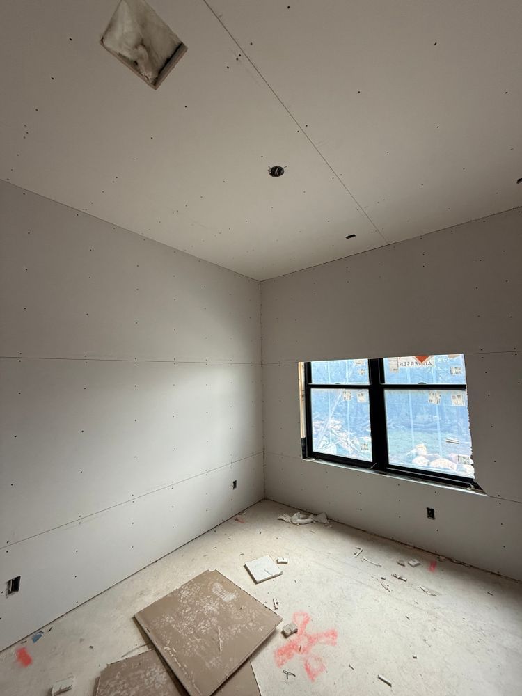 Empty unfinished room with gray walls, white floor, a window, and construction debris on the floor.
