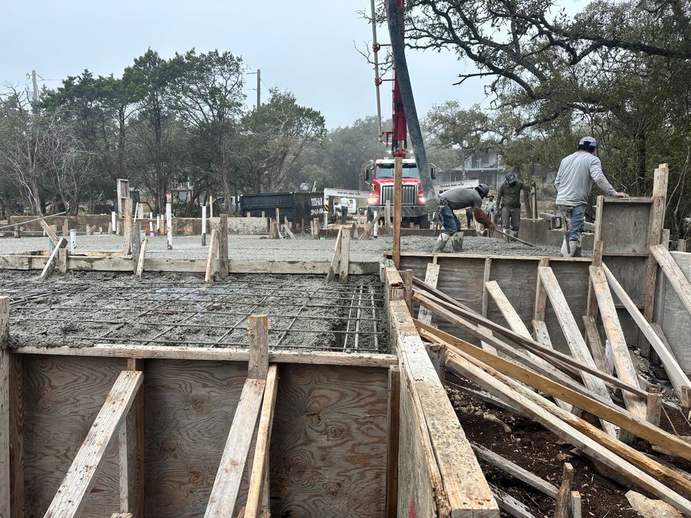 Concrete foundation work with wooden forms and workers at a construction site