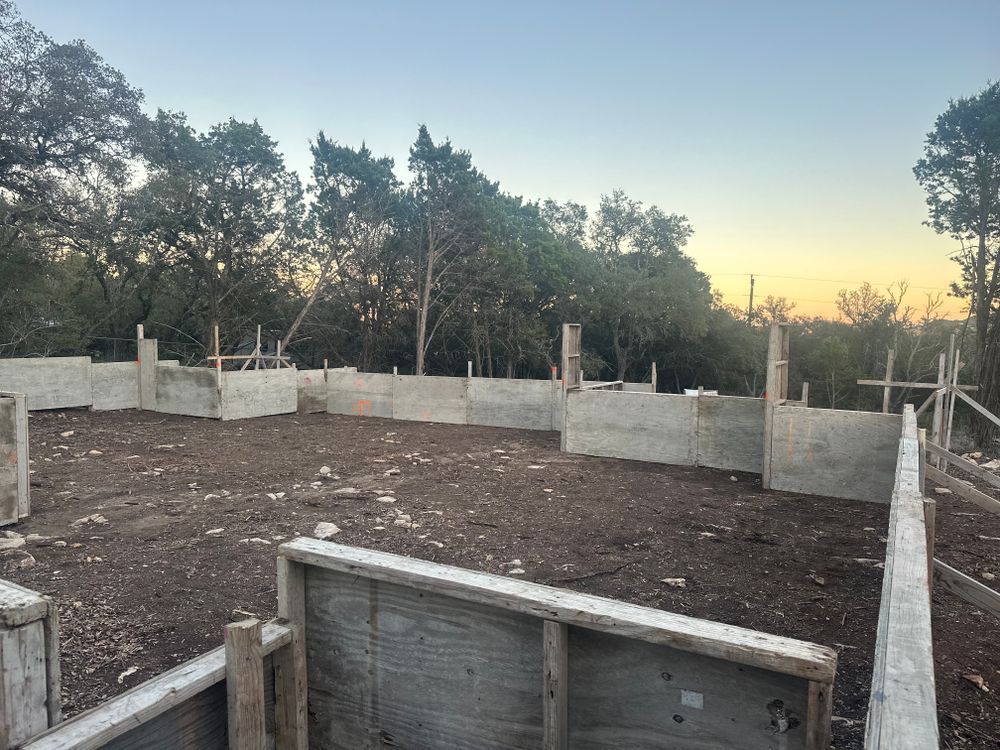 Partially built concrete foundation at sunset, with trees surrounding the site.
