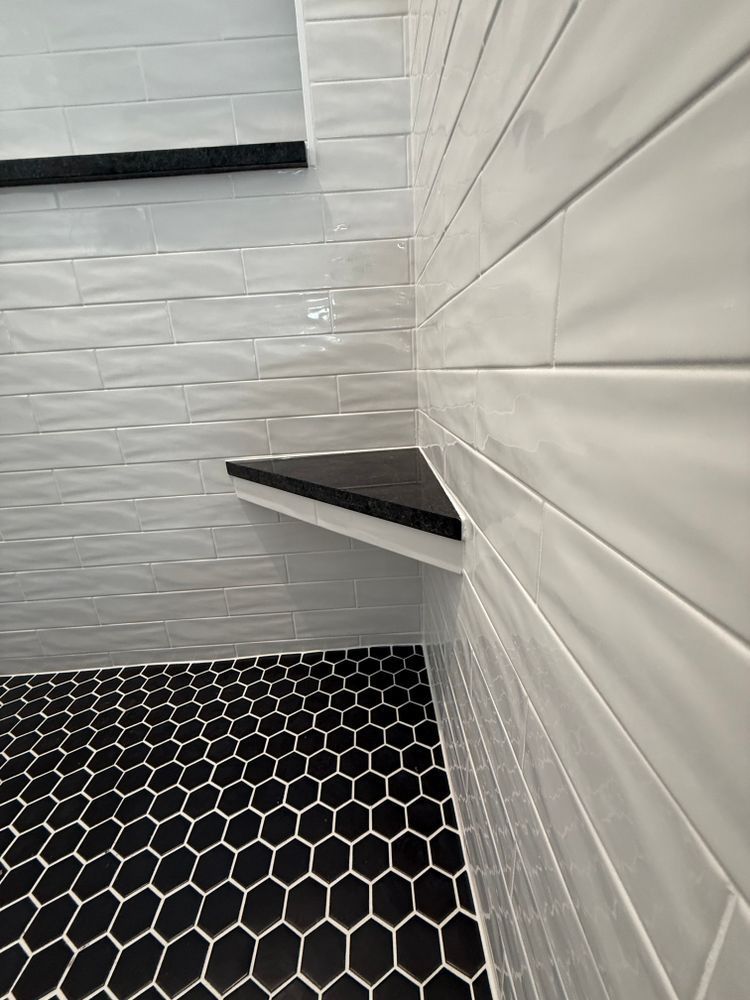 White tiled stairwell with black hexagon floor and a small wall shelf