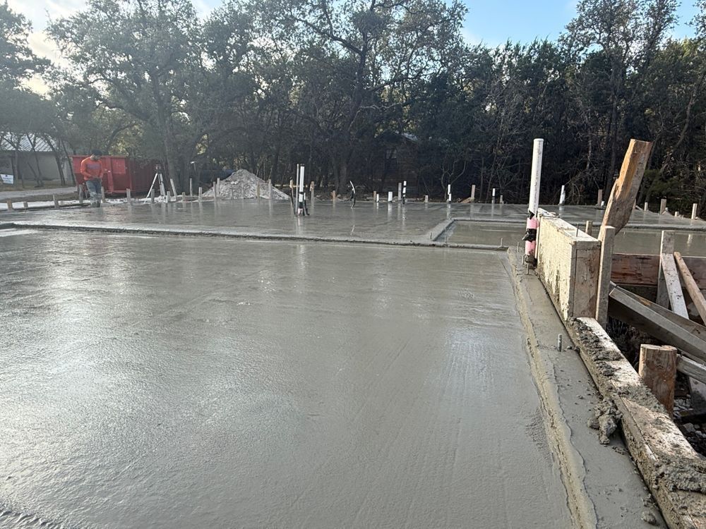 Fresh concrete slab being poured at a construction site with trees in the background