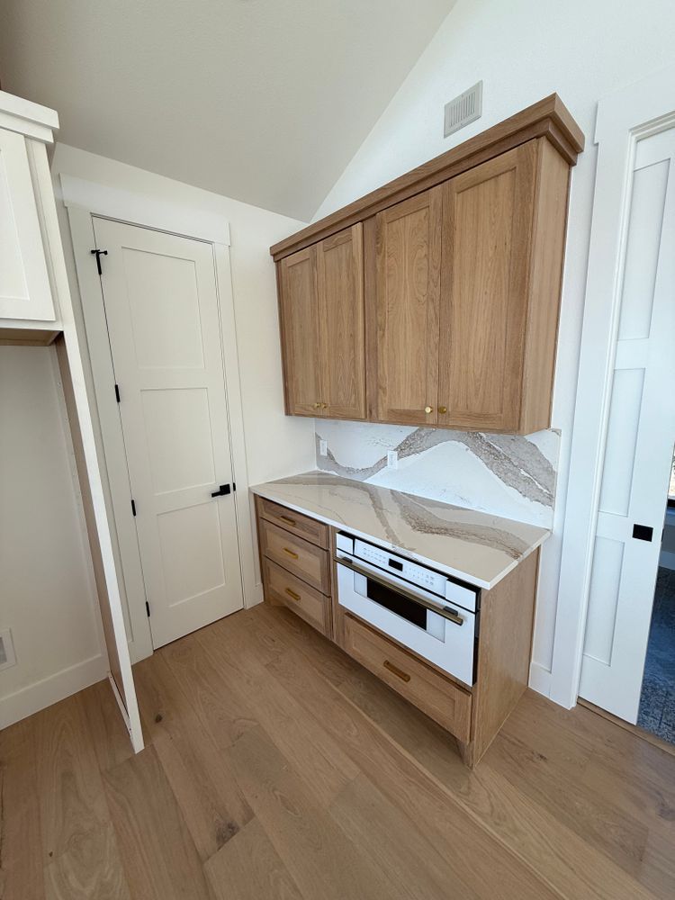 Small modern kitchen with wood cabinets, white countertops, and light wood flooring