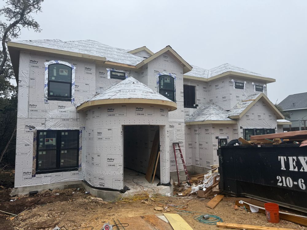 Partially built two-story white house with a front porch and construction debris