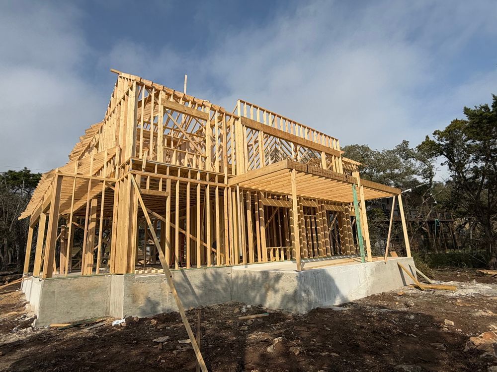 Wood-framed house under construction on a concrete foundation under a cloudy sky