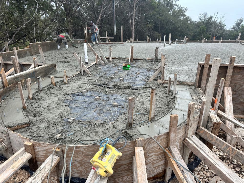 Circular concrete foundation under construction with wooden forms and workers in the background