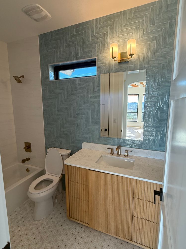 Modern bathroom with blue textured accent wall, vanity, toilet, and tub/shower.