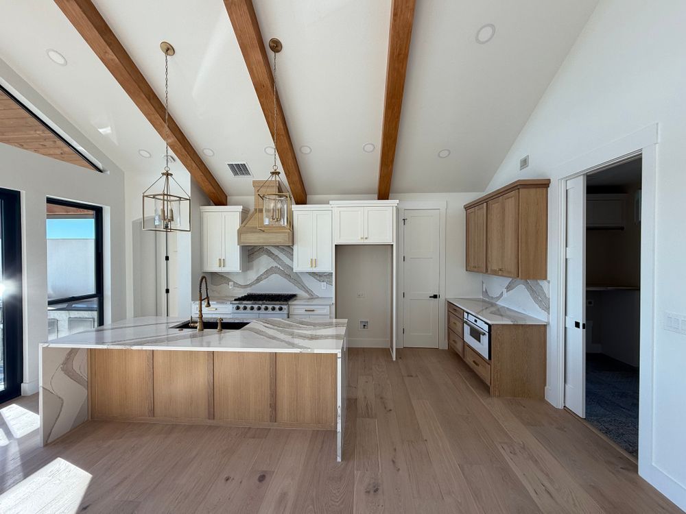 Spacious modern kitchen with wood beams, white cabinets, and a large island with pendant lights.