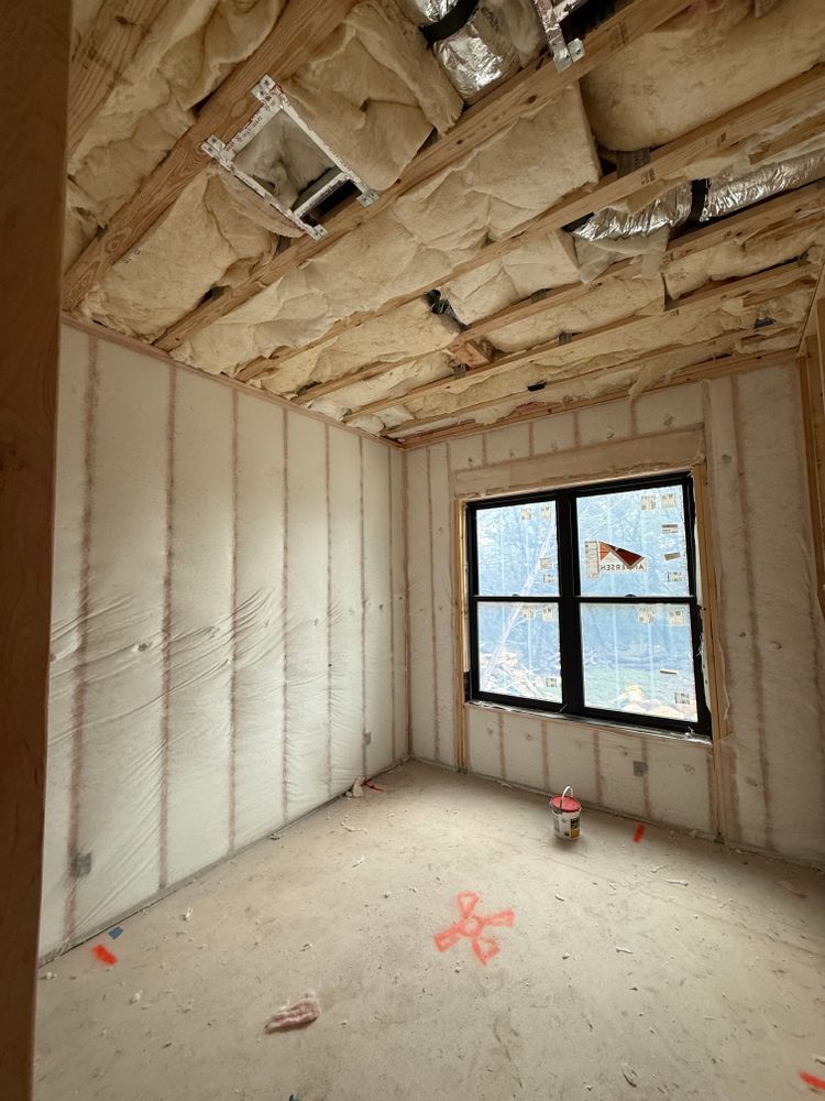 Unfinished room with insulated walls, exposed ceiling, and a window showing snow outside.