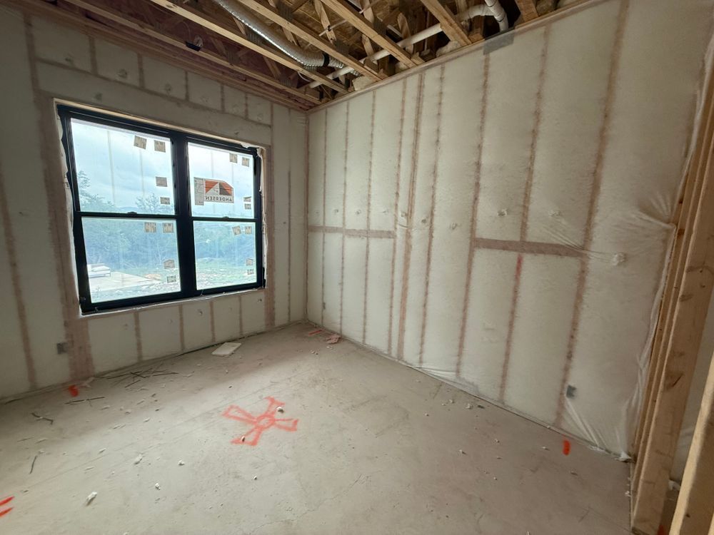 Unfinished room with insulated walls, exposed ceiling joists, and a window letting in daylight.