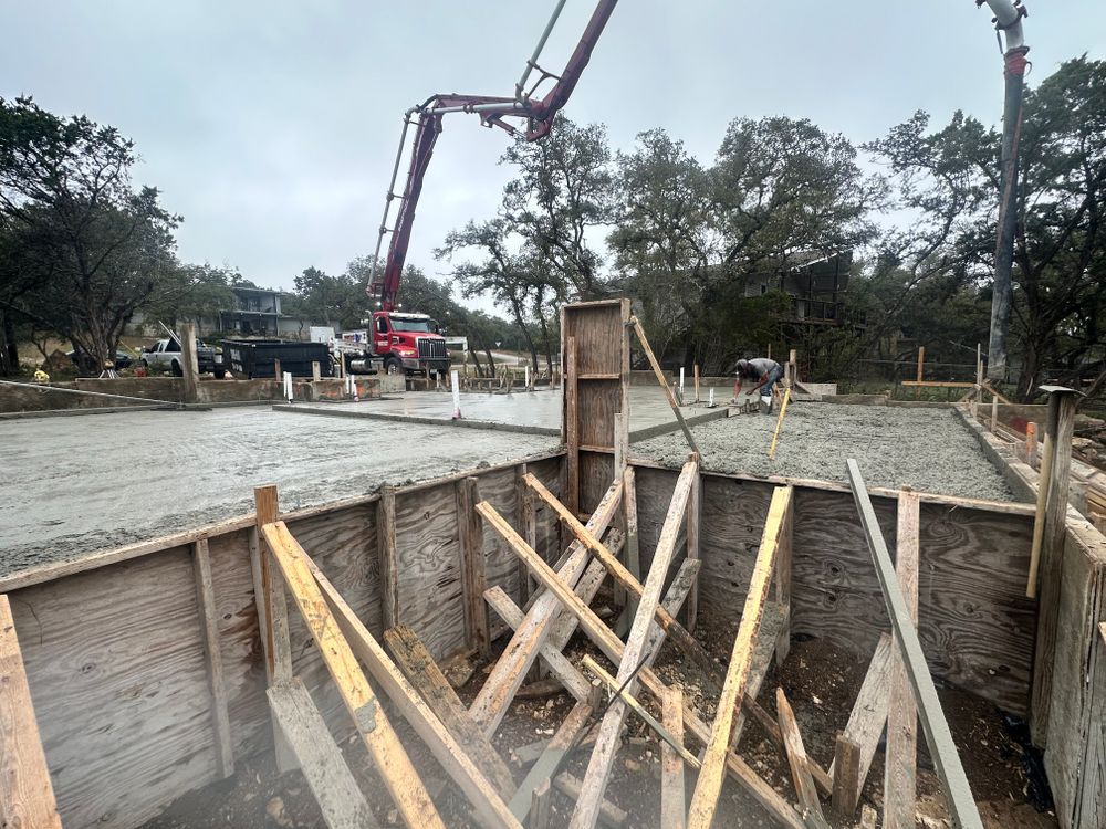 Concrete pour site with wooden forms and a pump truck arm over a foundation trench