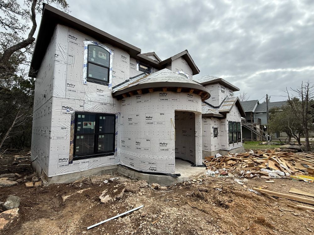 Partially built two-story house with white exterior siding and construction debris in front