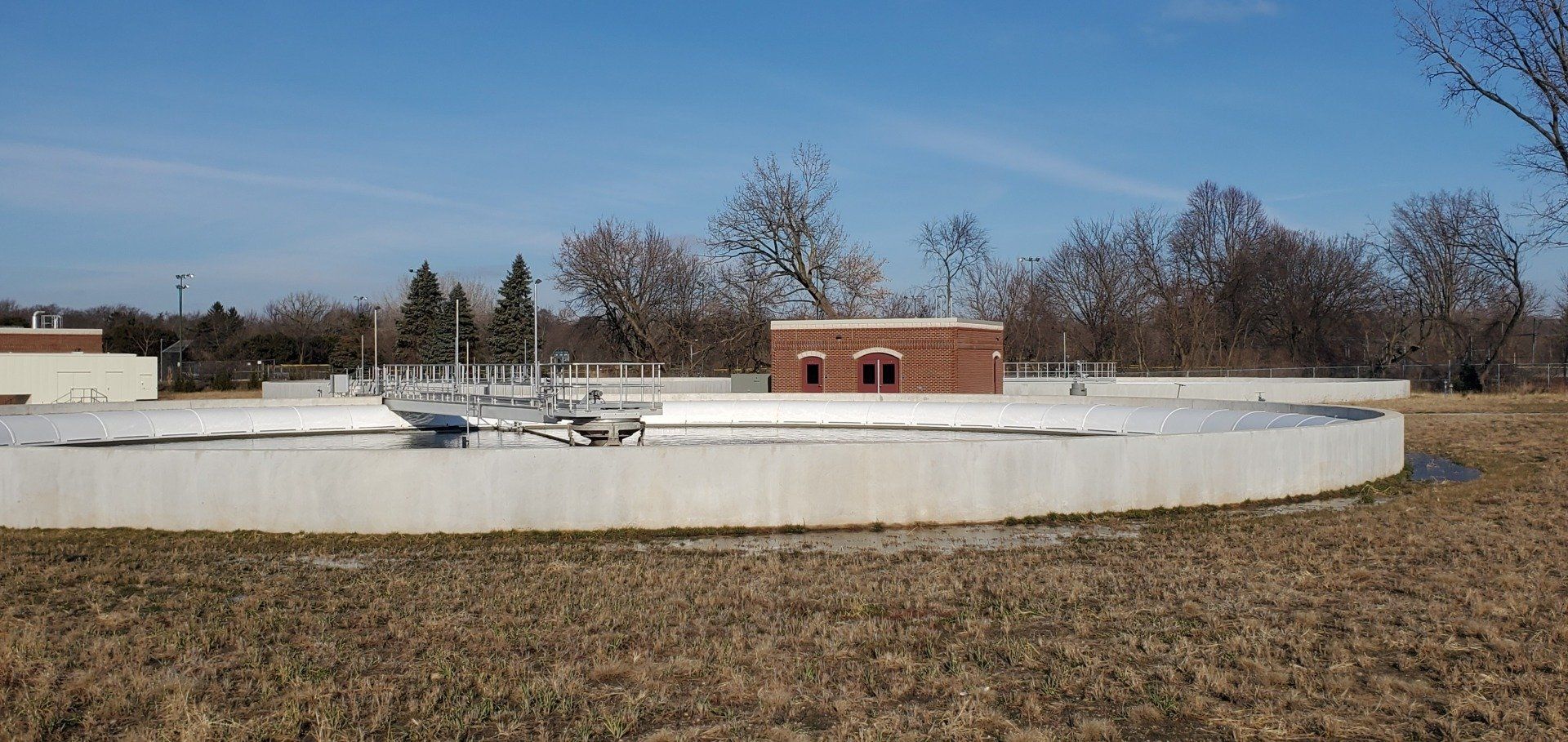 A large body of water in the middle of a field with a building in the background.