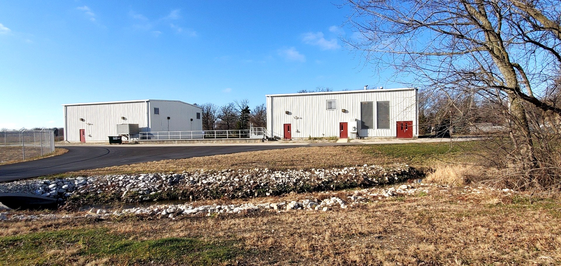 A large white building with red doors is sitting in the middle of a field.