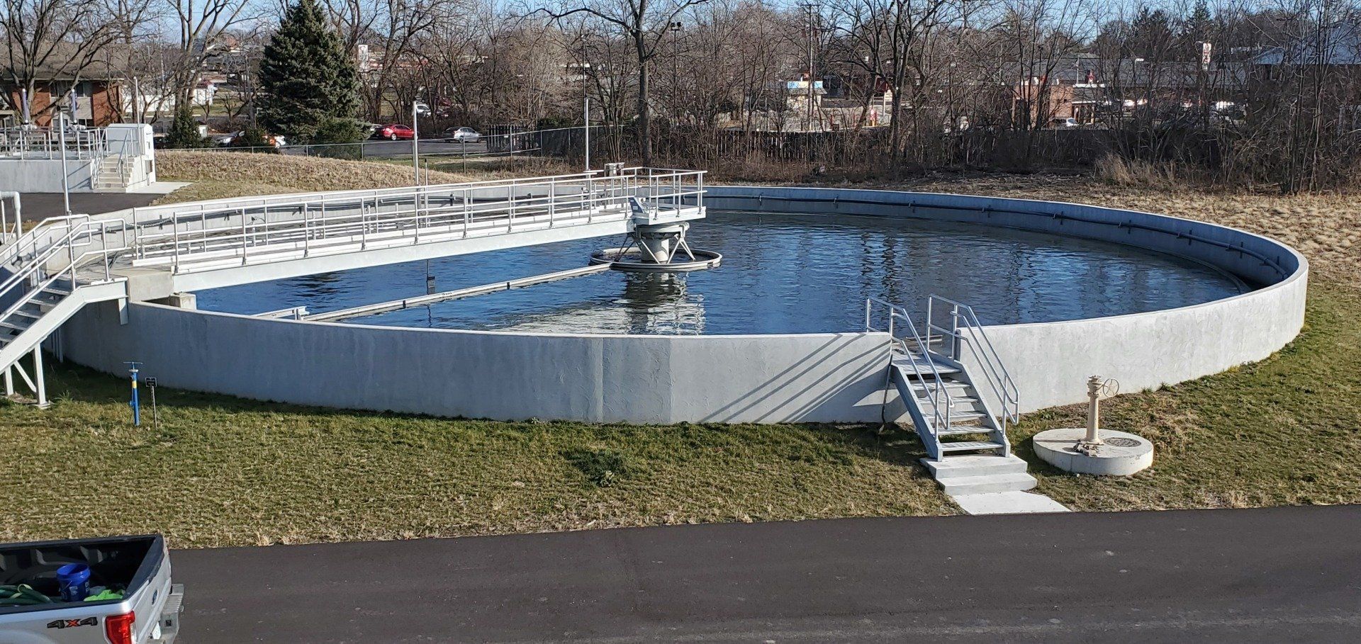 A white truck is parked in front of a large pool of water.