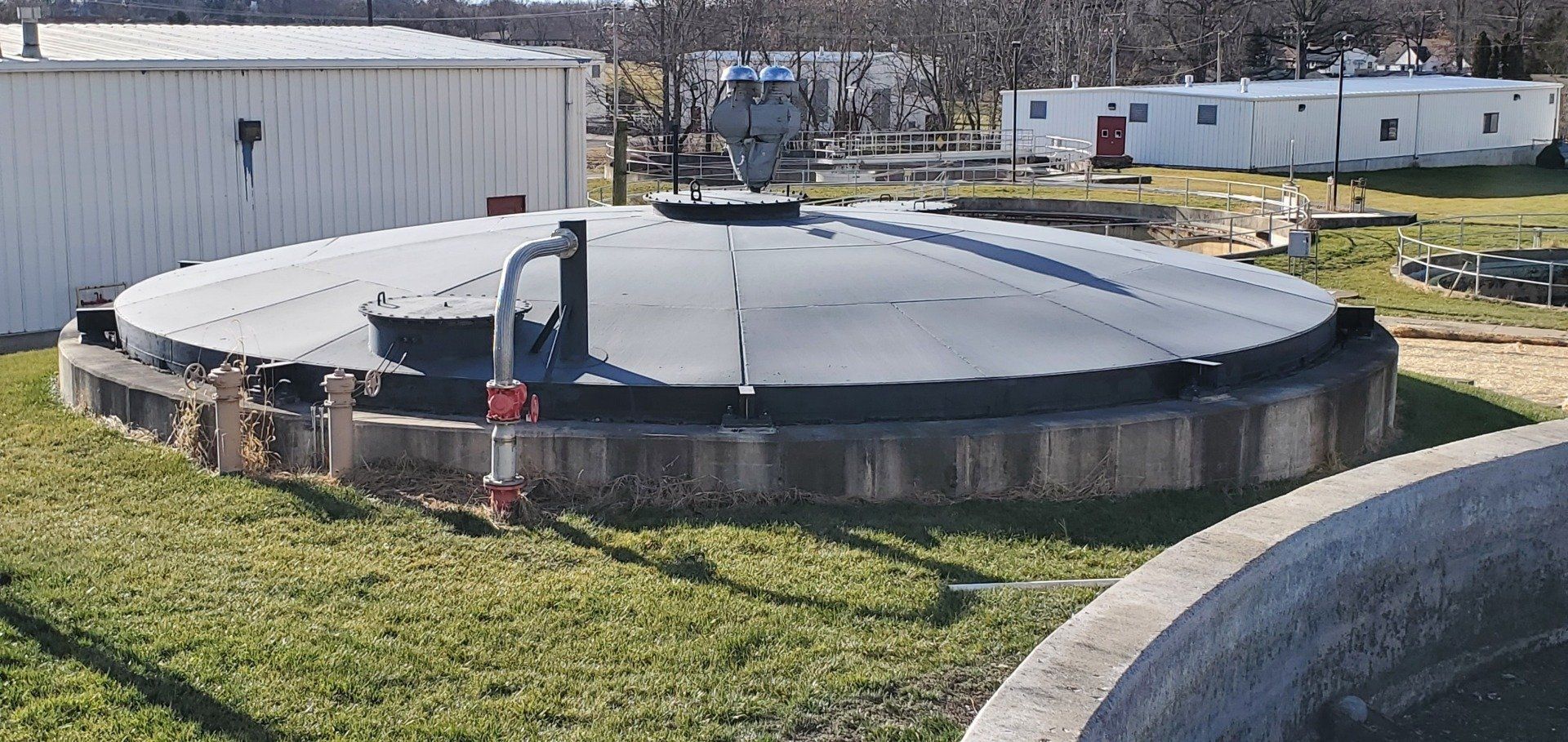 A large concrete tank is sitting on top of a lush green field.